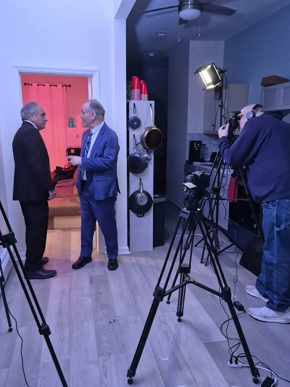 Behind-the-scenes on a GreenRose set: two actors in suits performing in a doorway while a camera operator films with professional lighting